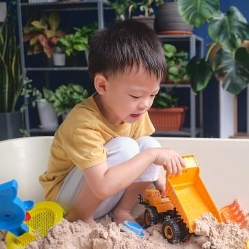 young boy playing in sandpit