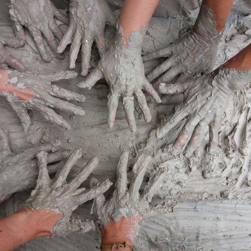 multiple hands playing in a pile of mud and covered in mud
