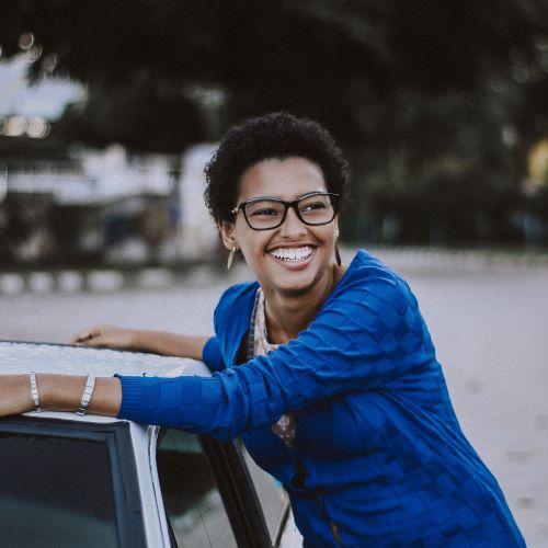 a profile picture of a woman leaning on a car and smiling