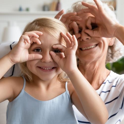a young girl and her grandmother circling their eyes with their hands like glasses