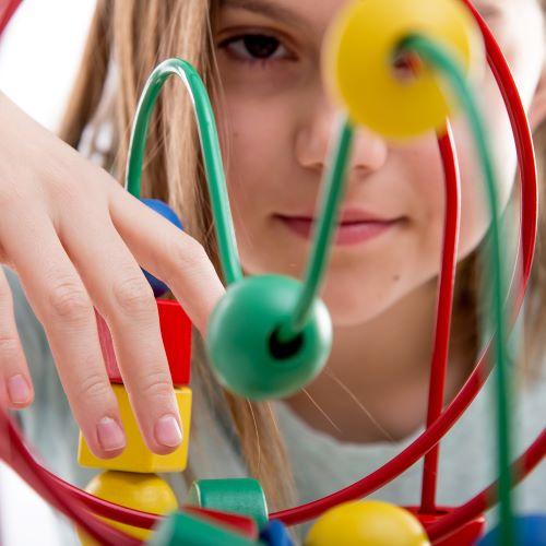 a young girl playing with a bead and metal toy