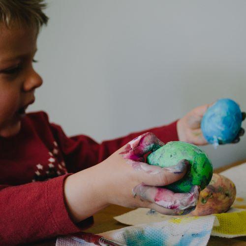 a young boy holding play dough in his hands